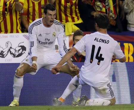 Real Madrid's Gareth Bale celebrates his goal with his teammate Xabi Alonso (R) during their King's Cup final soccer match against Barcelona's at Mestalla stadium in Valencia April 16, 2014. REUTERS/Albert Gea