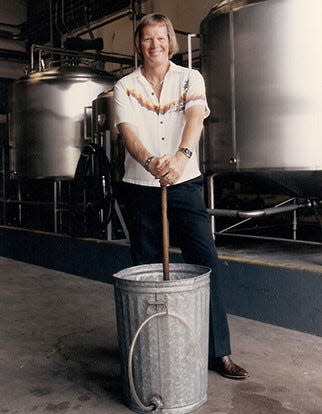 Ron Rice, in the 1980s, with the original garbage can and broom stick he used to make his first batch of Hawaiian Tropic.