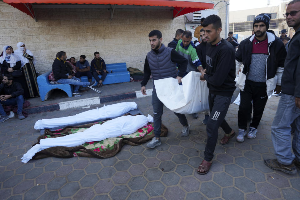 Palestinos cargan a un familiar muerto en el bombardeo israelí sobre la Franja de Gaza, ante la morgue del hospital en Deir al Balah, en la Franja de Gaza, el lunes 18 de diciembre de 2023. (AP Foto/Adel Hana)