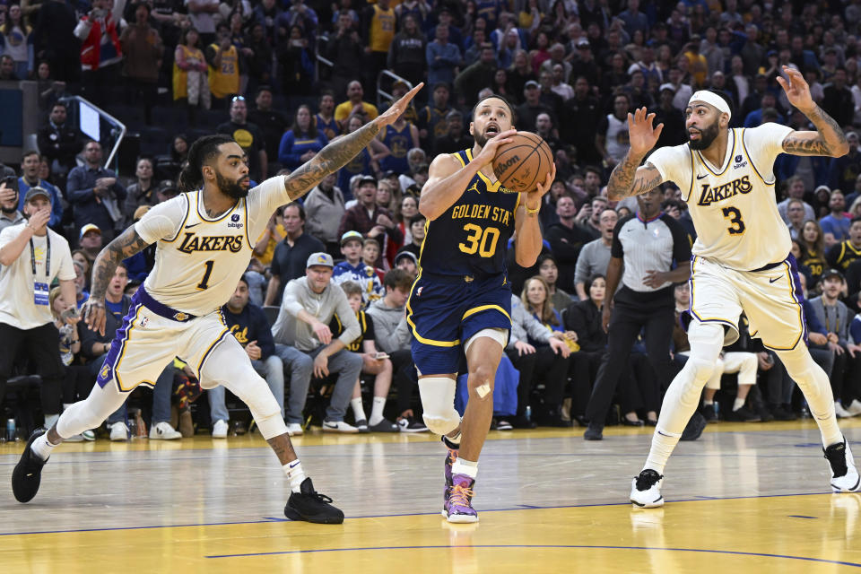 Los Angeles Lakers guard D'Angelo Russell (1) and forward Anthony Davis (3) defend against Golden State Warriors guard Stephen Curry (30) during the second half of an NBA basketball game Saturday, Jan. 27, 2024, in San Francisco. (AP Photo/Nic Coury)