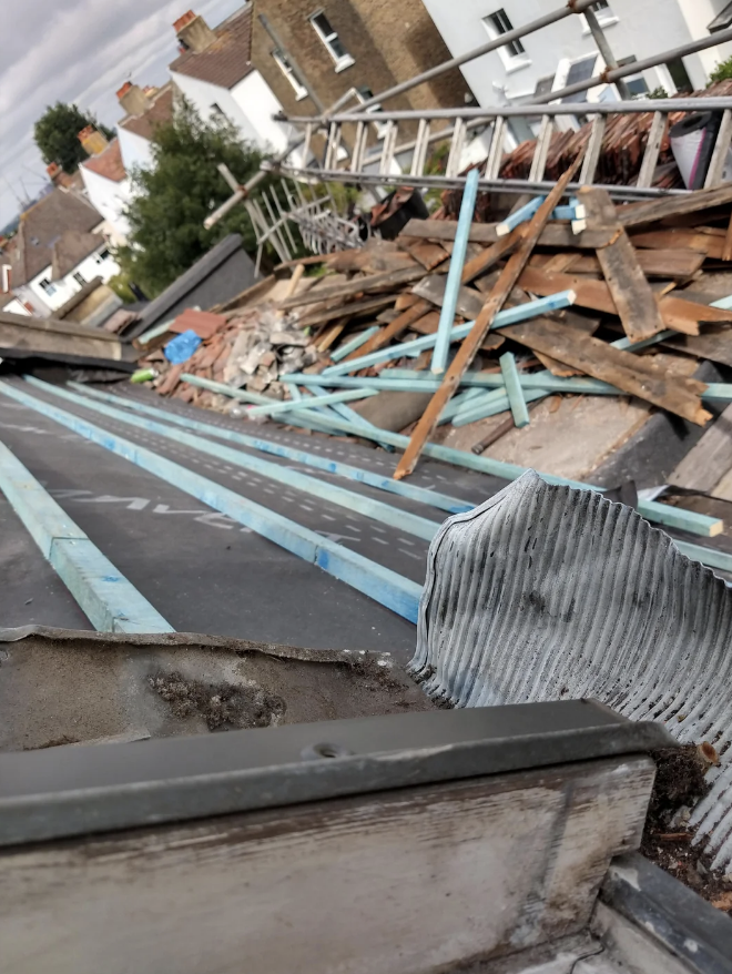 Assorted construction debris and materials on a rooftop with surrounding buildings in the background