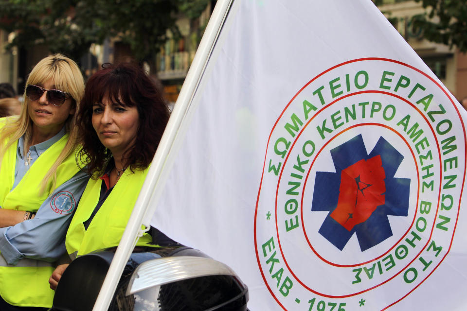 Greek paramedics and first aid workers stand next to their union's flag during a protest against pay and funding cuts outside the Health Ministry in Athens, on Tuesday, Oct. 16, 2012. Greece has been surviving on emergency loans from eurozone countries and the International Monetary Fund for more than two years. It is currently locked in protracted negotiations with rescue creditors for a major new austerity package that is set to take the country into a sixth year of recession in 2013. (AP Photo/Thanassis Stavrakis)