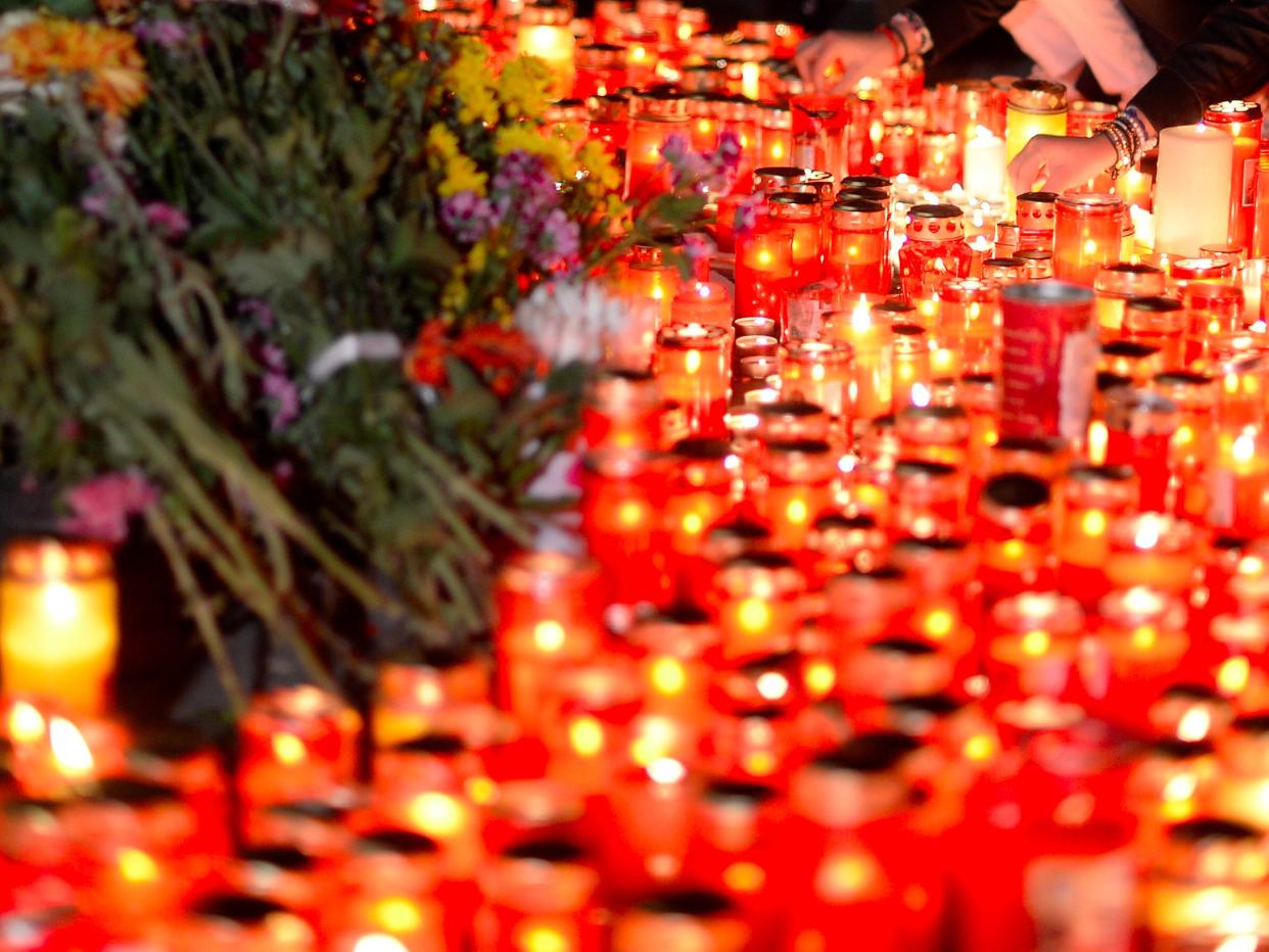 People light candles outside a nightclub, where a fire broke out on Friday, in Bucharest, Romania October 31, 2015.