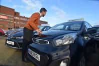 Ameen Sultani looks inside a car as he shows some of the older, cheaper vehicles that have been popular with customers eager to avoid public transport during the coronavirus disease (COVID-19) pandemic, in Hayes