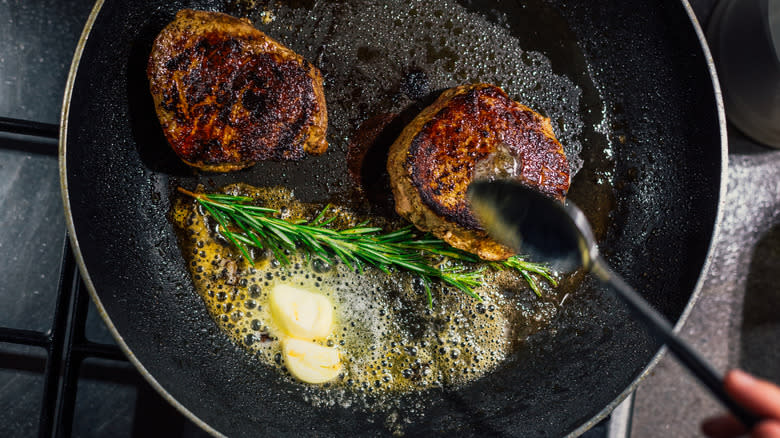 Home cook butter-basting two steaks