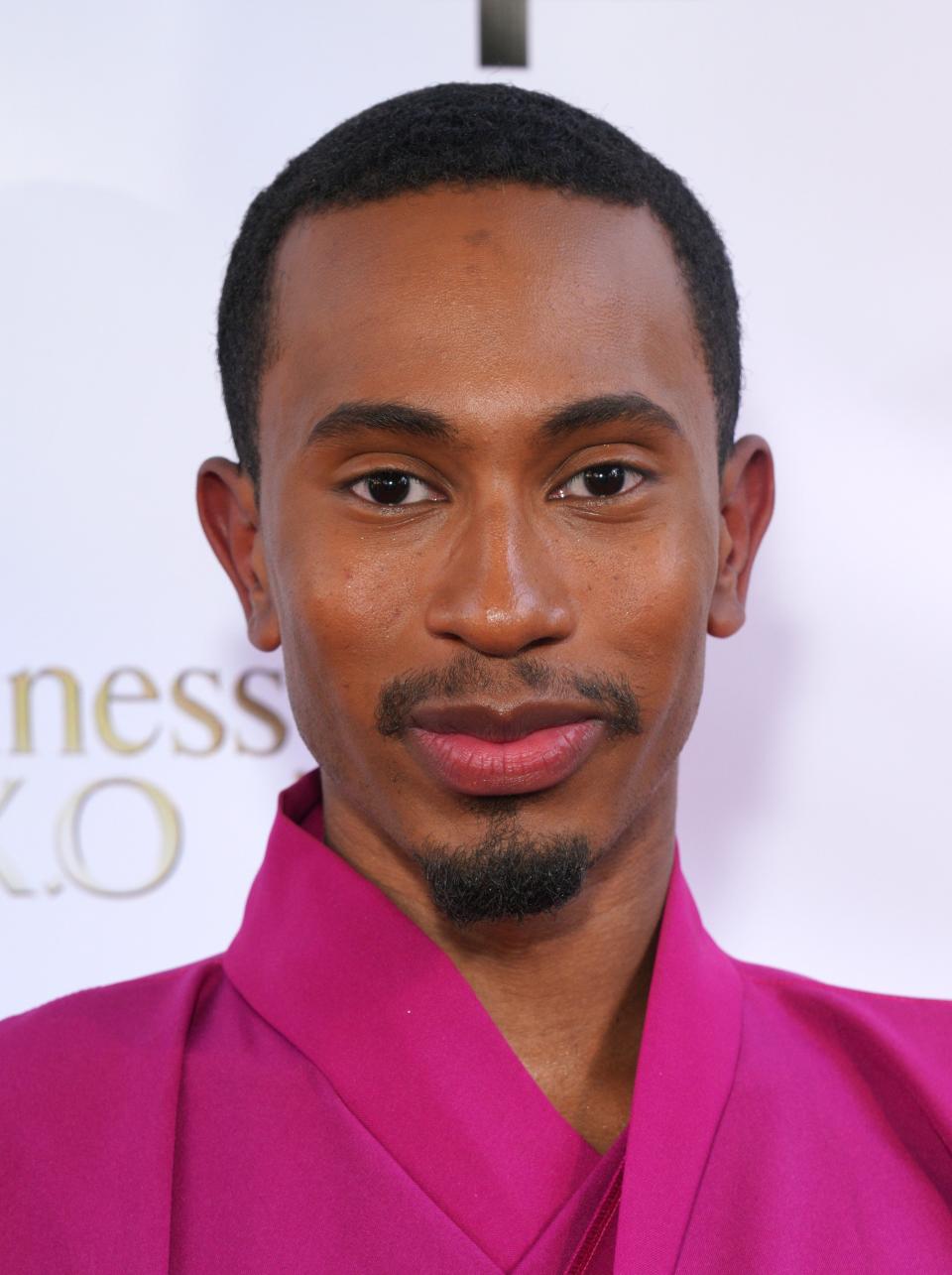Kalen in a stylish pink suit jacket posing at a celebrity event