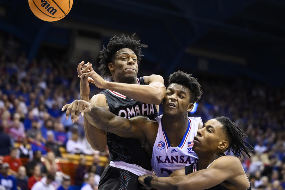 Kansas forward K.J. Adams Jr. (24) is sandwiched between Omaha guard Jaeden Marshall, left, and Omaha forward Marquel Sutton, right, during the first half of an NCAA college basketball game in Lawrence, Kan., Monday, Nov. 7, 2022. (AP Photo/Reed Hoffmann)