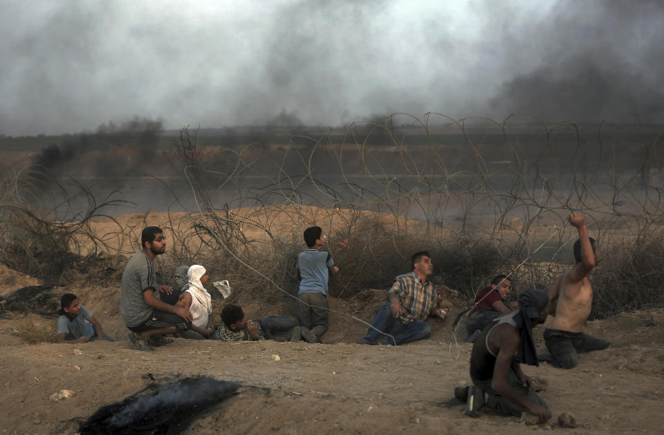 Palestinian protesters take a cover during a protest at the Gaza Strip's border with Israel, Friday, Oct. 19, 2018. (AP Photo/Khalil Hamra)