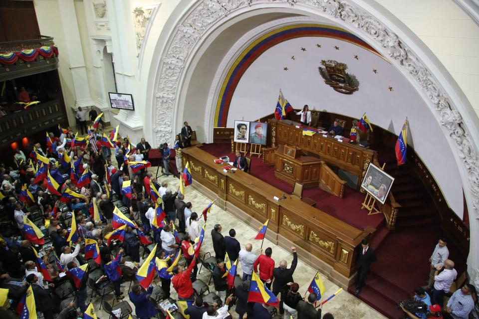 Members of the National Constituent Assembly wave Venezuelan flags during a session by the legislative body that is stacked with government allies that rivals the opposition-controlled National Assembly in Caracas, Venezuela, Monday, Aug. 12, 2019. Legislators loyal to Venezuelan President Nicolás Maduro on Monday stripped immunity from four opposition lawmakers accused of treason amid a struggle for control of the crisis-stricken nation, bringing to 18 the number of opposition politicians Maduro's government has threatened with criminal prosecution this year. (AP Photo/Leonardo Fernandez)