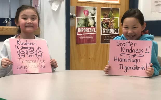 Two students from Helen Kalvak Elihakvik School in Ulukhaktok, N.W.T. show the signs they made to celebrate Pink Shirt Day. Each sign the students made were in English and Inuinnaqtun and included phrases of kindness.