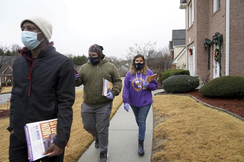 Robert Campbell, Graco Hernandez Valenzuela and Stephanie Lopez-Burgus, from left, canvas a neighborhood for the Working Families Party about the U.S. Senate races, Wednesday, Dec. 16, 2020, in Lawrenceville, Ga. (AP Photo/Tami Chappell)