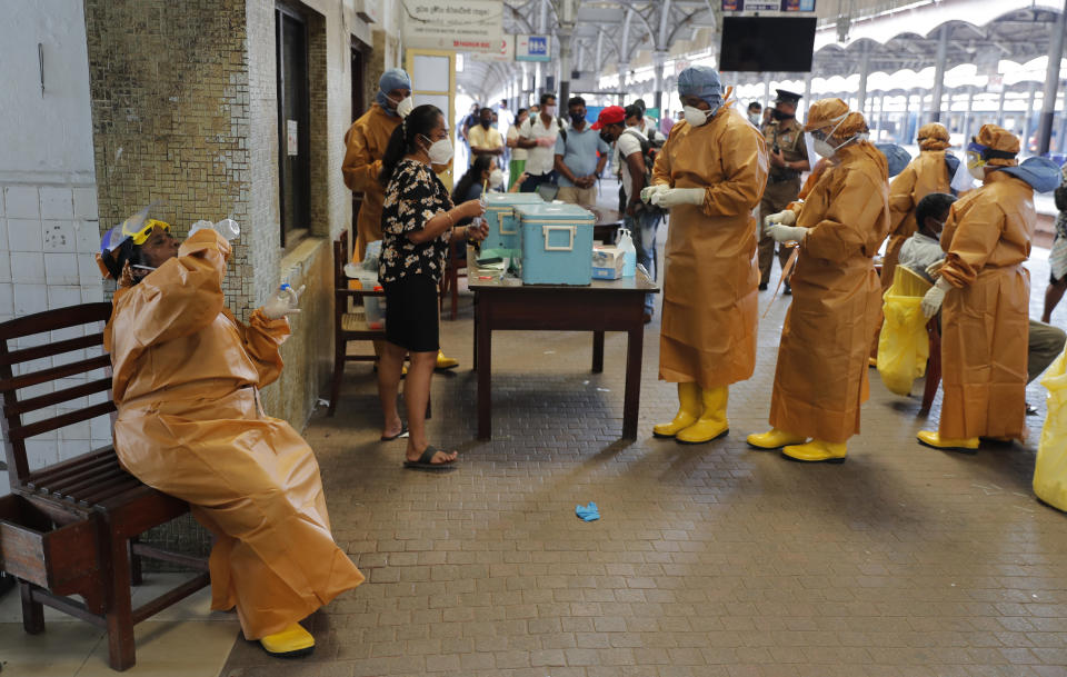 A health officer collecting swab samples from rail commuters to test for COVID-19 drinks water during a break at a railway station in Colombo, Sri Lanka, Monday, Oct. 12, 2020. (AP Photo/Eranga Jayawardena)