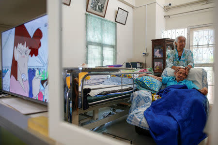 Nopawan Pullbangyung, 67, massages her husband Serm Pullbangyung, 75, at her house in Nonthaburi, Thailand, April 24, 2016. REUTERS/Athit Perawongmetha