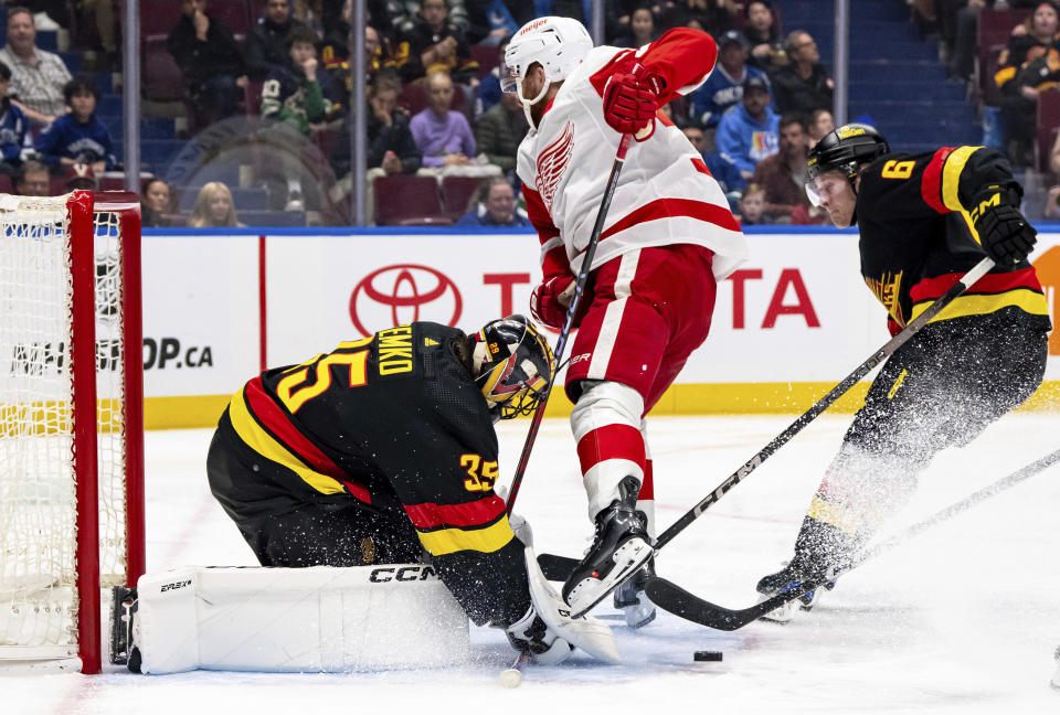 Vancouver Canucks goaltender Thatcher Demko (35) stops Detroit Red Wings' J.T. Compher (37) as Vancouver's Brock Boeser (6) watches during the second period of an NHL hockey game Thursday, Feb. 15, 2024, in Vancouver, British Columbia. (Ethan Cairns/The Canadian Press via AP)