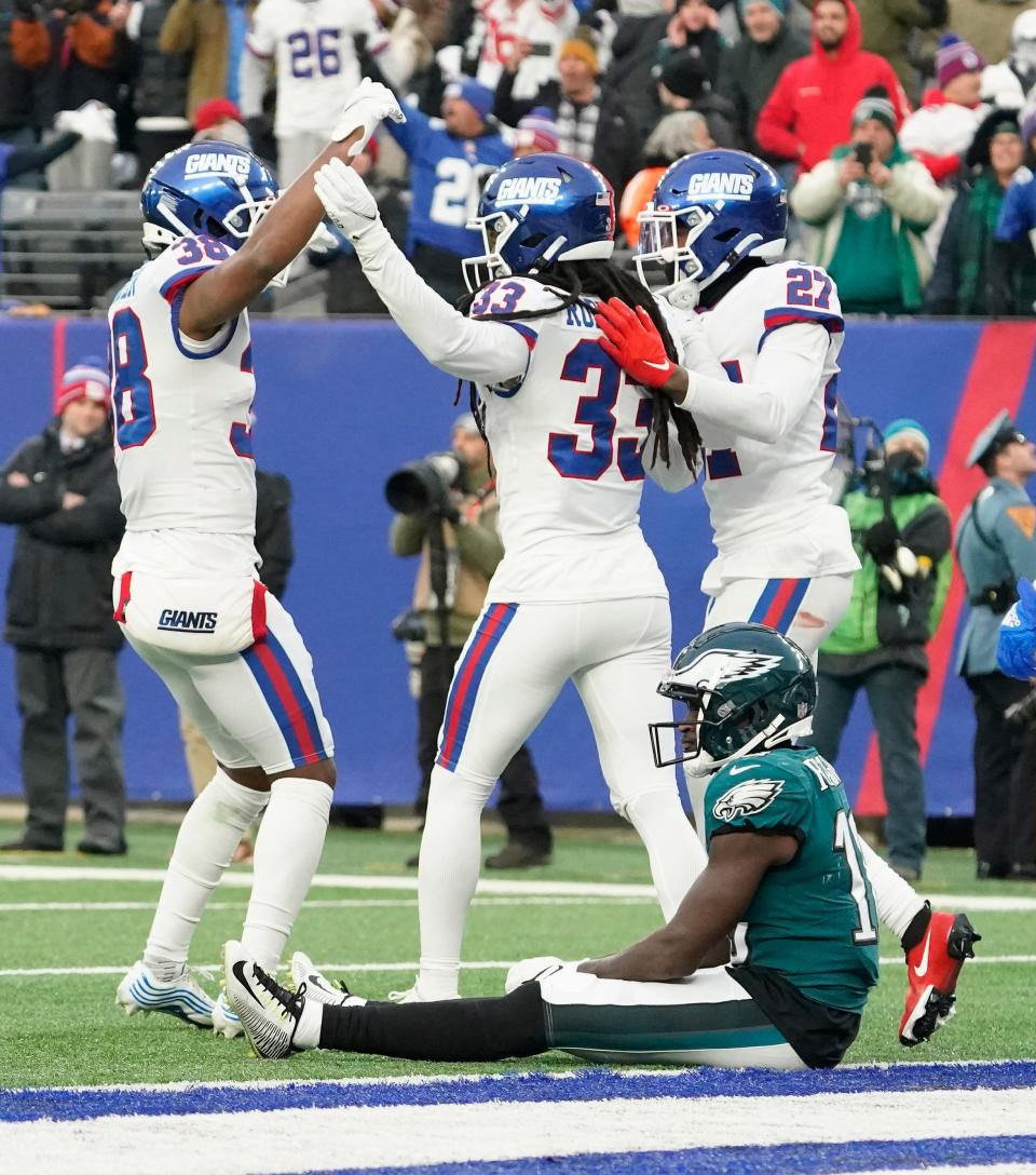 New York Giants defenders celebrate as Philadelphia Eagles wide receiver Jalen Reagor, bottom, reacts after dropping a potential game-winning touchdown with seconds left in the game.