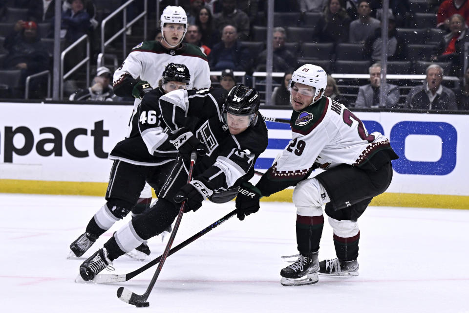 Los Angeles Kings right wing Arthur Kaliyev, center, shoots against Arizona Coyotes center Barrett Hayton, right, during the second period of an NHL hockey game in Los Angeles, Thursday, Dec. 1, 2022. (AP Photo/Alex Gallardo)