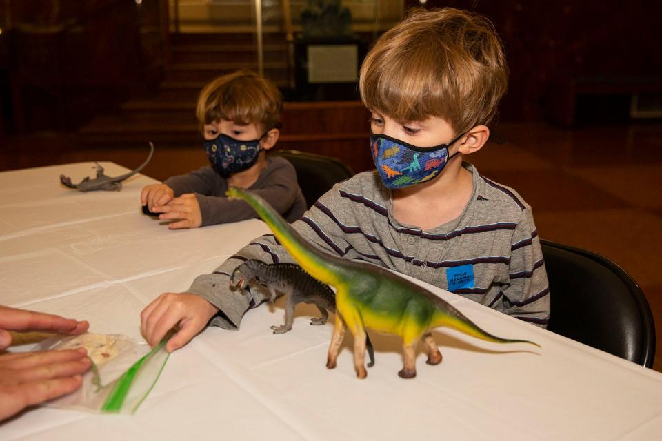 Elliott Peters, 4, right, and Parker Peters, 2, create dinosaur-themed ornaments at the Texas Memorial Museum on Friday.