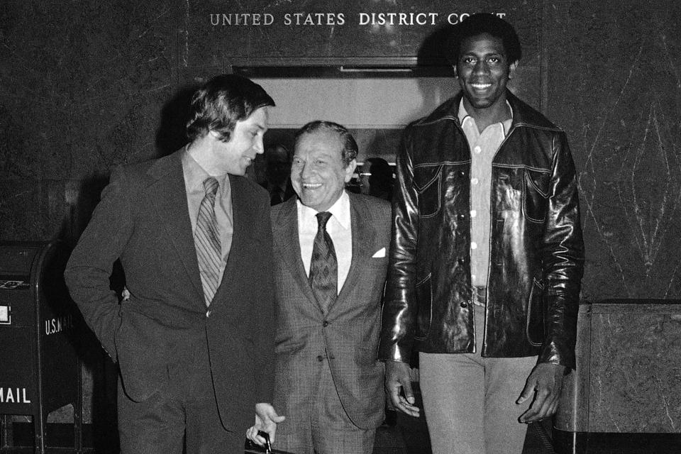 FILE - Basketball star Spencer Haywood leaves U.S. district court in Los Angeles Jan. 8, 1971, with attorney Al Ross, left, and president Sam Schulman of the Seattle SuperSonics of the NBA after a judge ruled in effect for and against him in his law suit against the NBA. The ruling permits Haywood to resume play with the SuperSonics, but continues a temporary restraining order against the NBA to give Haywood's attorneys time to file a cause of action which would require evidence of anti-trust violation. (AP Photo/Wally Fong, File)