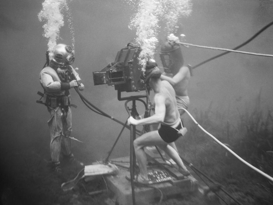 An underwater camera crew makes close up of a diver actor to show the correct method of adjusting an air valve in 1944.