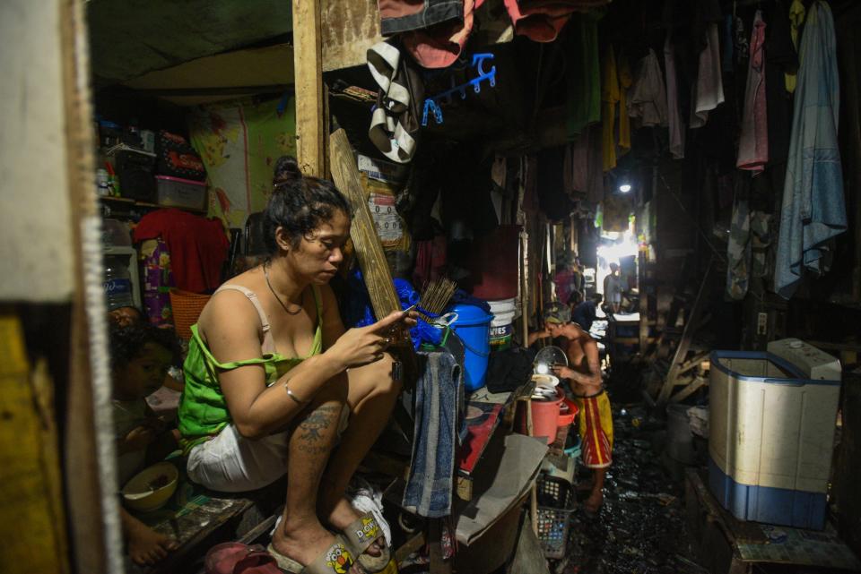This photo taken on March 18, 2020 shows a woman checking her phone outside her home in Manila. - Asian nations have imposed increasingly heavy measures to fight the outbreak of the COVID-19 coronavirus, the Philippines has ordered half its population of some 110 million to stay home. (Photo by Maria TAN / AFP) / TO GO WITH Health-virus-Philippines-poverty,FOCUS by Joshua Melvin and Ron Lopez (Photo by MARIA TAN/AFP via Getty Images)
