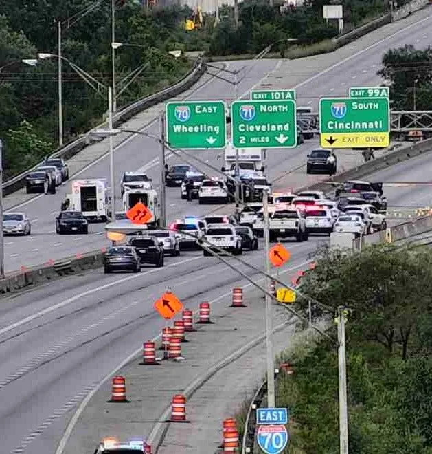 Police vehicles on I-70 at Mound Street near Downtown surround a stolen Porsche Cayenne SUV, just beneath the I-71 South sign, as officers responded to a Columbus police officer shot by robbery suspects Thursday afternoon.