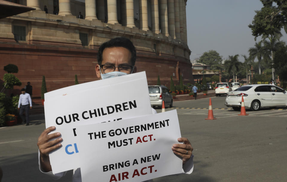 FILE- In this Nov.18, 2019, file photo, opposition lawmaker Gaurav Gogoi holds placards protesting against the alarming levels of pollution in the city on the opening day of the winter session of the Parliament in New Delhi, India. India is grappling with two public health emergencies: critically polluted air and the pandemic. Nowhere is this dual threat more pronounced than in the Indian capital New Delhi, where the spike in winter pollution levels has coincided with a surge of COVID-19 cases. (AP Photo/Manish Swarup, File)