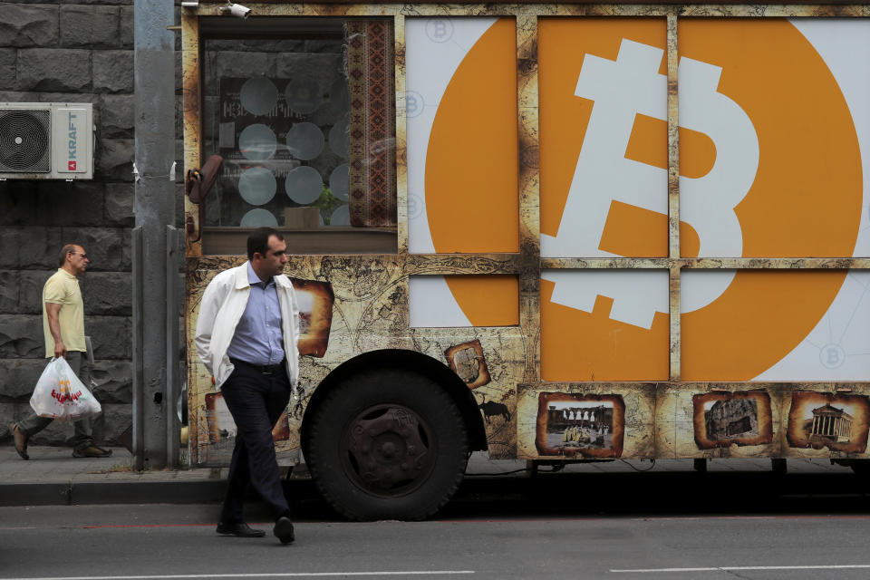 People walk past a board with the logo of Bitcoin in a street in Yerevan, Armenia September 9, 2019. REUTERS/Anton Vaganov