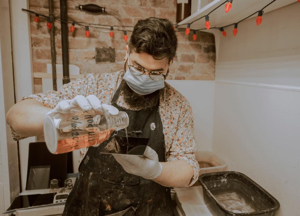 Rudy Salgado pours collodion onto a metal plate before taking a tintype portrait at River City Tintype studio in Louisville, Kentucky. Jan. 12, 2022.