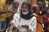 A women makes a phone call as she holds a picture of a victim of a soccer riots provided by volunteers for identification purpose, at a hospital in Malang, East Java, Indonesia, Sunday, Oct. 2, 2022. Panic at an Indonesian soccer match Saturday left a number of people dead, most of whom were trampled to death after police fired tear gas to dispel the riots. (AP Photo/Dicky Bisinglasi)