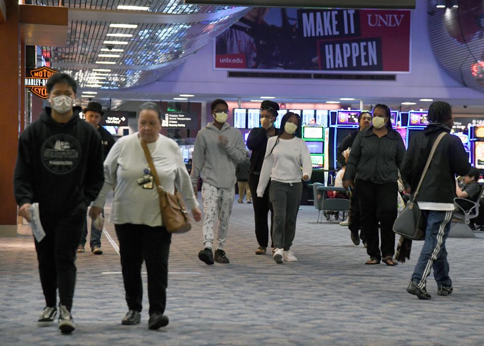 People, some wearing masks, walk through a concourse at McCarran International Airport as the coronavirus continues to spread across the United States on March 19, 2020 in Las Vegas, Nevada.