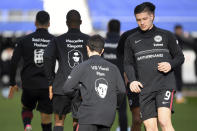 Frankfurt's players wear the pictures and names of the victims of the shooting in Hanau a year ago on their training jackets, prior to the German Bundesliga soccer match between Eintracht Frankfurt and Bayern Munich in Frankfurt, Germany, Saturday, Feb. 20, 2021. A right-wing extremist shot dead nine people in Hanau on 19 Feb. 2020, before shooting himself. (Arne Dedert/POOL via AP)