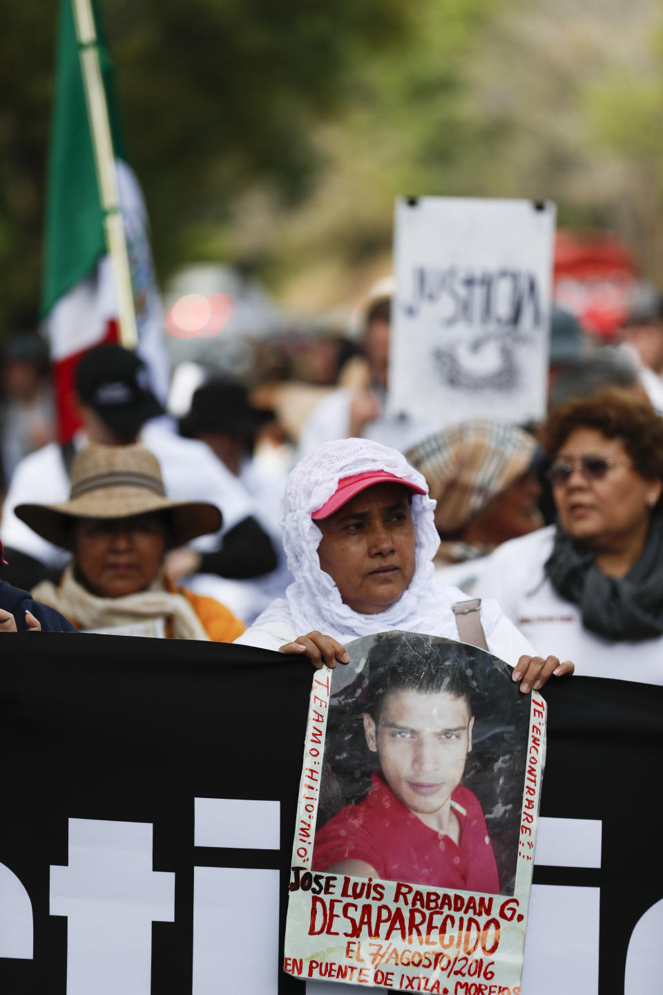 A woman holds a photograph that says in Spanish "Jose Luis Rabadan G. isappeared Aug. 7, 2016 on the bridge of Ixtla, Morelos. I love you my son. I will find you." during a march against violence called "Walk for Peace" as the group leaves Cuernavaca, Mexico, Thursday, Jan. 23, 2020, with Mexico City as their destination. Activist and poet Javier Sicilia is leading his second march against violence in Mexico, this time accompanied by members of the LeBaron family, and plan to reach Mexico's National Palace on Sunday. (AP Photo/Eduardo Verdugo)