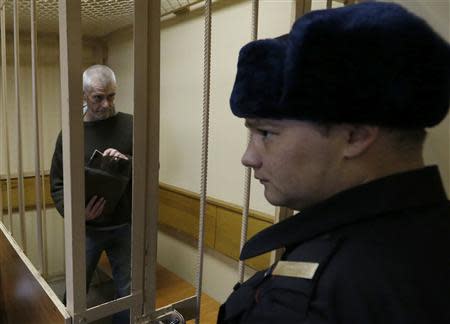 Greenpeace activist David John Haussmann of New Zealand, one of the 30 people who were arrested over a Greenpeace protest at the Prirazlomnaya oil rig, stands inside a defendants' cage as he attends a court session in St. Petersburg, November 19, 2013. REUTERS/Alexander Demianchuk