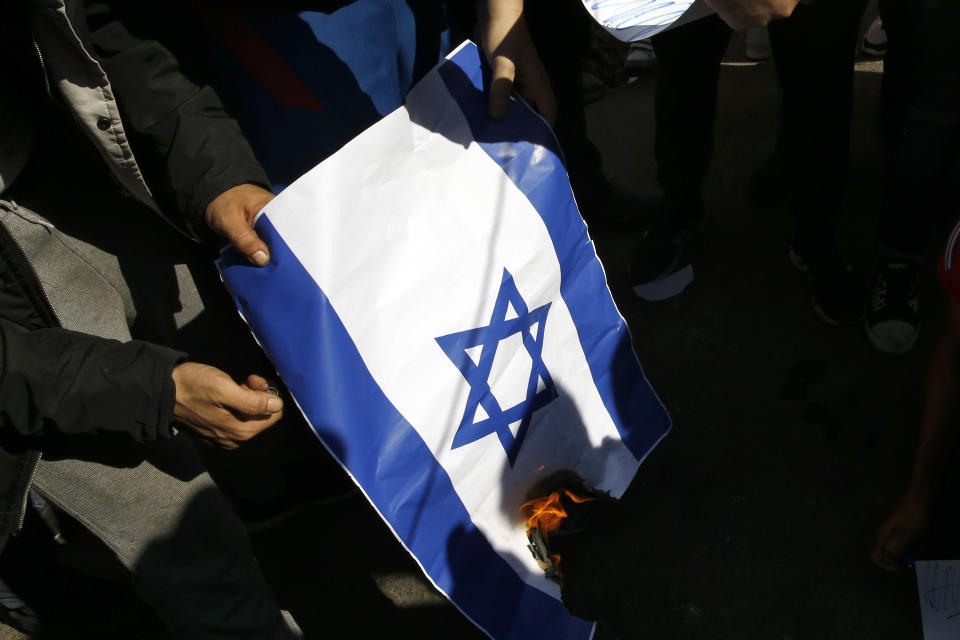 Anti-government protesters burn an Israeli flag after riot police open a road, in Beirut, Lebanon, Thursday, Oct. 31, 2019. Army units and riot police took down barriers and tents set up in the middle of highways and major intersections Thursday. (AP Photo/Bilal Hussein)