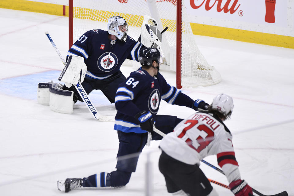 Winnipeg Jets' goaltender Connor Hellebuyck (37) makes a save on New Jersey Devils' Tyler Toffoli (73) during the third period of an NHL hockey game Tuesday, Nov. 14, 2023, in Winnipeg, Manitoba. (Fred Greenslade/The Canadian Press via AP)