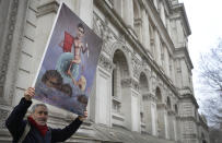 Artist Kaya Mar holds up his painting depicting Chancellor Rishi Sunak near Downing Street in London, Wednesday, March 3, 2021. Britain's Chancellor Rishi Sunak is expected to announce billions of pounds in tax cuts and spending increases to help workers and businesses hit by the coronavirus pandemic when he delivers his budget to Parliament on Wednesday. (AP Photo/Kirsty Wigglesworth)