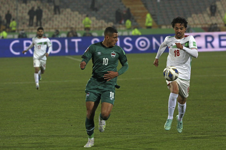 Iran's Omid Nor Afkan, right, and Iraq's Ali Ibrahim Alzubaidi run for the ball during their 2022 World Cup qualifier soccer match, at the Azadi stadium in Tehran, Iran, Thursday, Jan. 27, 2022. Iran became the first team from Asia to qualify for this year's World Cup in Qatar with a 1-0 win over Iraq. (AP Photo/Vahid Salemi)