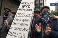 A group of restaurant owners and workers use a mock coffin as a prop while while protesting outside the building which houses New York Gov. Andrew Cuomo's office, Monday, Sept. 28, 2020, in New York. The group is calling for expanded outdoor dining and that indoor dining to be expanded from 25 to 50 percent occupancy. (AP Photo/Mary Altaffer)