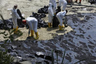 Workers clean oil spill along Sentosa's Tanjong Beach area in Singapore, Sunday, June 16, 2024. (AP Photo/Suhaimi Abdullah)