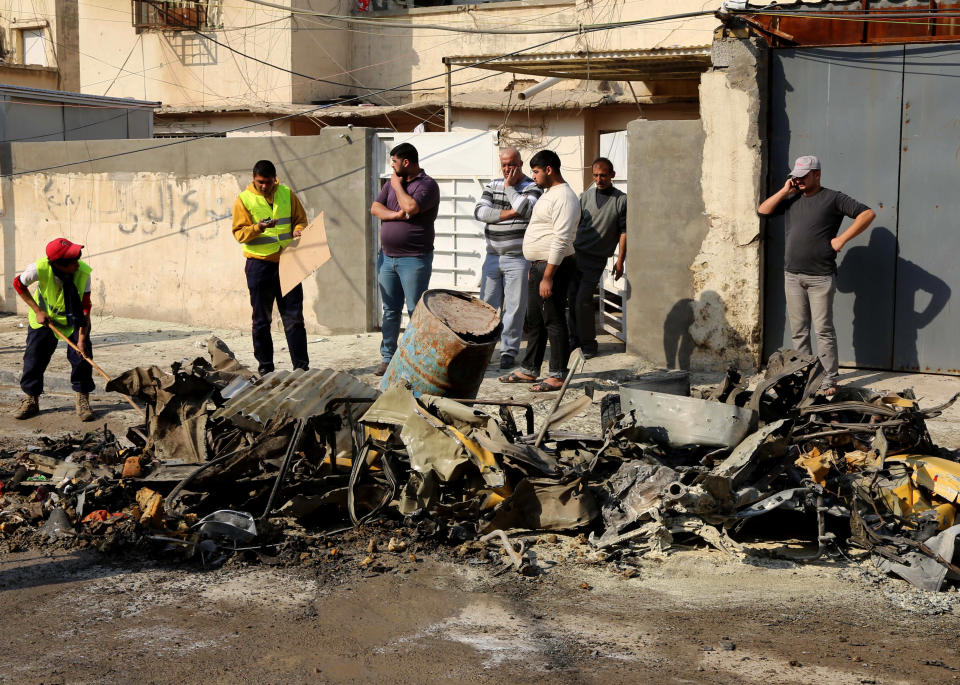 Baghdad municipality workers clean up as civilians inspect the site of a car bomb attack near the Technology University in Sinaa Street in downtown Baghdad, Iraq, Wednesday, Jan. 15, 2014. A wave of bombings across Iraq striking busy markets and a funeral north of Baghdad killed tens of people Wednesday, authorities said, as the country remains gripped by violence after al-Qaida-linked militants took control of two cities in western Anbar province. (AP Photo/Karim Kadim)