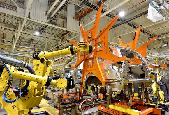 A scene from the assembly line: Two large yellow robots are putting body panels on an SUV's frame.