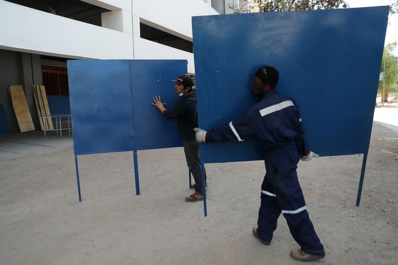 Workers carry sections of voting booths inside a polling station ahead of the upcoming referendum on a new Chilean constitution in Santiago,
