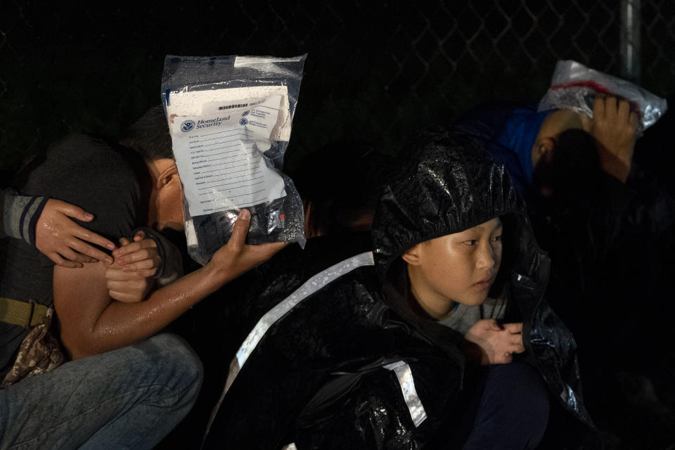 A man and a woman embrace each other as rain falls on migrants being processed by immigration officials at the Fronton Cemetery #2 after they crossed the Texas-Mexico border, Friday, May 12, 2023, in Fronton, Texas. (AP Photo/Julio Cortez)