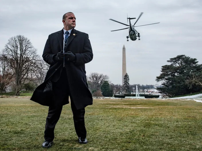 A Secret Service agent stands watch as President Trump departs on Marine One from the White House.