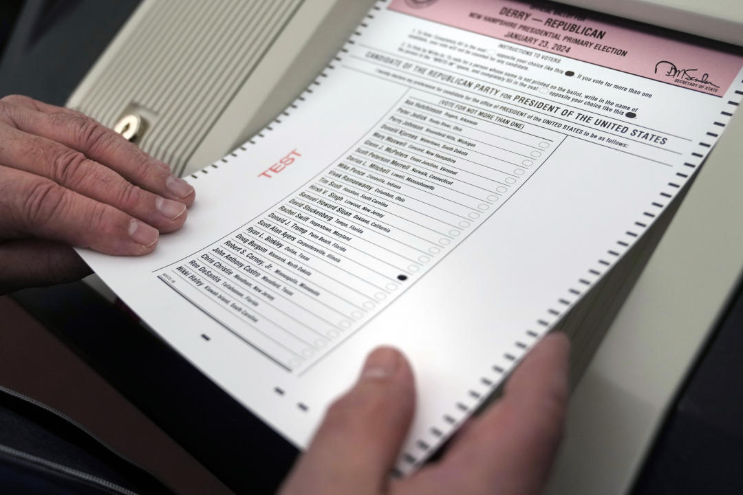 Two hands place a test ballot into a vote counting machine.