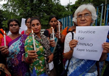 Women hold candles during a vigil demanding justice for a woman who is fighting a rape case against a legislator of the ruling BJP, in Kolkata