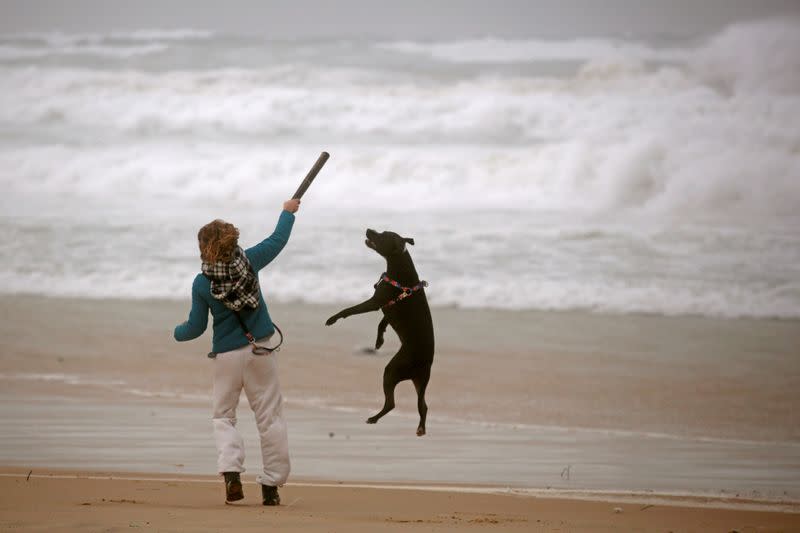 FILE PHOTO: A woman plays with her dog during a storm in Zikim beach, on the Mediterranean coast near the southern city of Ashkelon