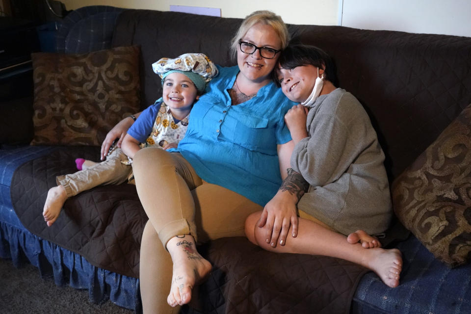 In this July 28, 2021 photo, Christina Darling and her sons, Brennan, 4, left, and Kayden, 10, pose for a photo at home in Nashua, N.H. Darling and her family have qualified for the expanded child tax credit, part of President Joe Biden's $1.9 trillion coronavirus relief package. "Every step closer we get to a livable wage is beneficial. That is money that gets turned around and spent on the betterment of my kids and myself," said Darling, a housing resource coordinator who had been supplementing her $35,000-a-year salary with monthly visits to the Nashua Soup Kitchen and Shelter's food pantry. (AP Photo/Elise Amendola)