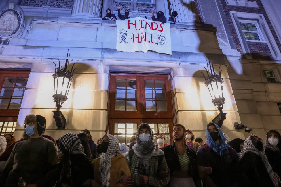 Protesters stand in front of Columbia's Hamilton Hall, which has a sign draped over it reading "Hinds Hall"