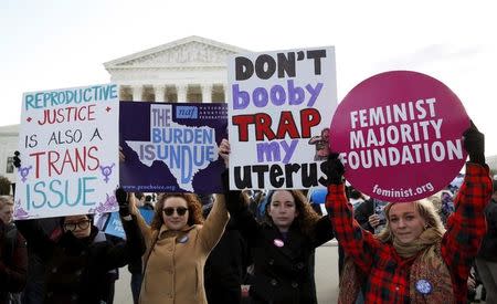 Protesters hold signs in front of the U.S. Supreme Court on the morning the court takes up a major abortion case focusing on whether a Texas law that imposes strict regulations on abortion doctors and clinic buildings interferes with the constitutional right of a woman to end her pregnancy, in Washington March 2, 2016. REUTERS/Kevin Lamarque